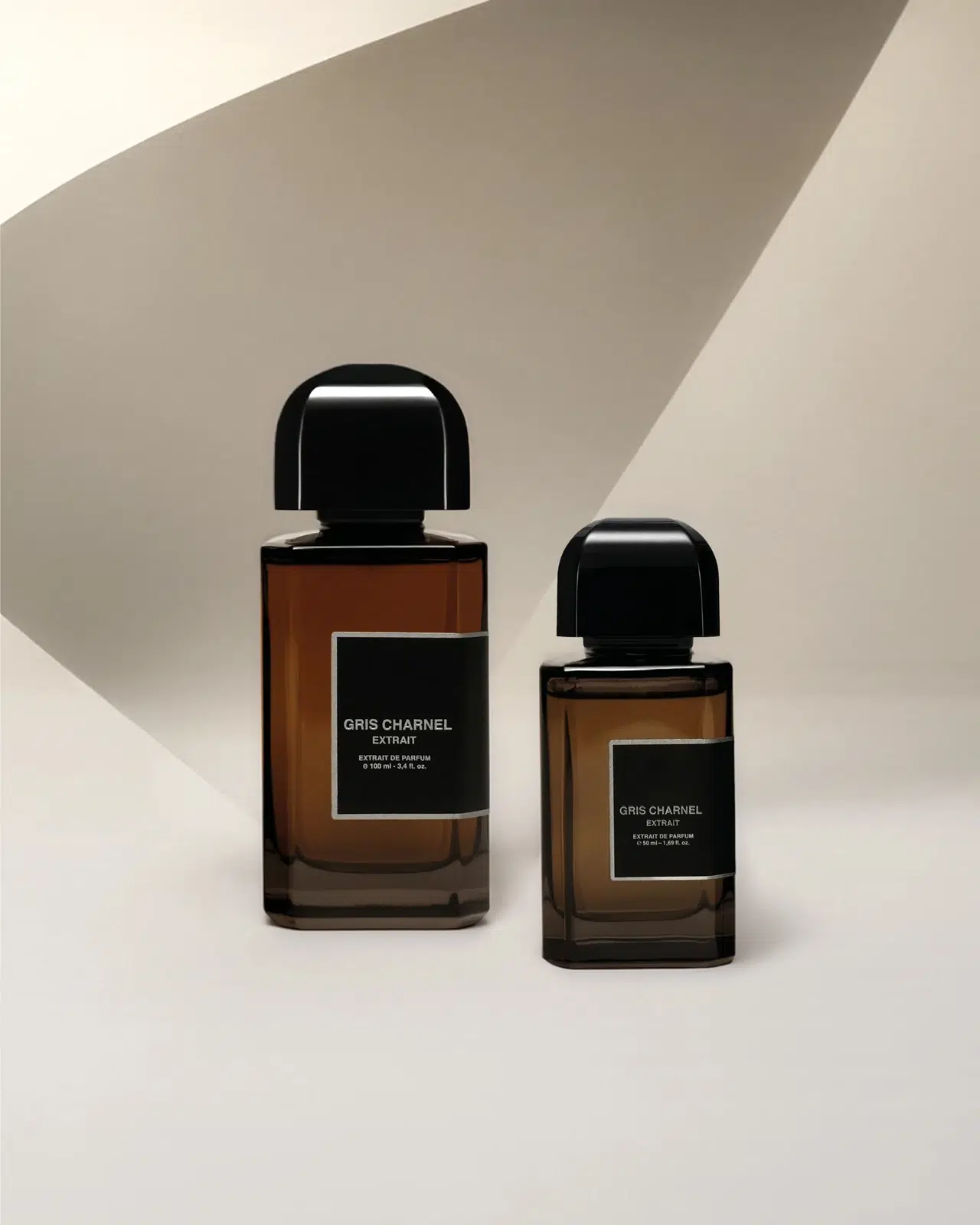 Два флакони BDK Parfums Gris Charnel Extrait на світлій поверхні в геометричному малюнку сонячних тіней