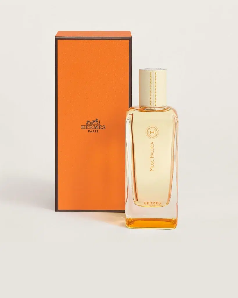 Флакон Hermès Musc Pallida з кремовою шкіряною кришкою поруч із помаранчевою коробкою Hermès на світлому тлі